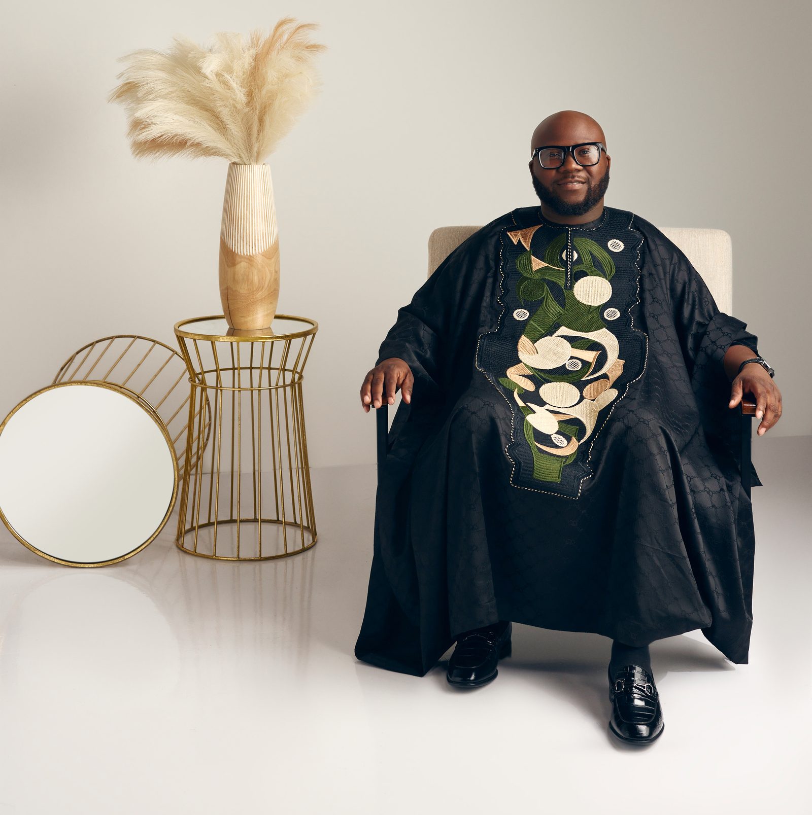 Victor Akinde seated in a black embroidered agbada